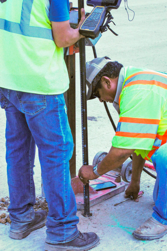 Bettis checking core sample depths of remilled asphalt with GPS Survey 08312020 2 685x1024